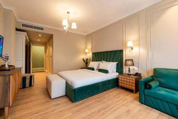 Schlafzimmer im Diamma Resort mit einem großen Bett, grüner Kopfstütze, Nachttischen und einer Couch.