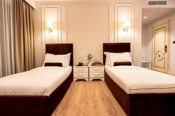 Zwei Betten in einem eleganten Schlafzimmer im Diamma Resort mit weißen Laken und Kopfkissen.