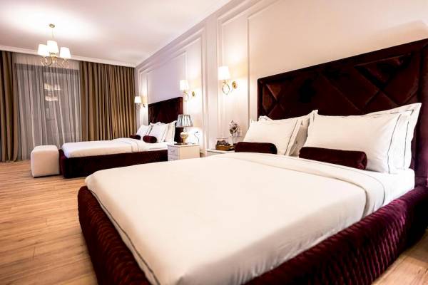 Schlafzimmer im Diamma Resort mit zwei Betten, weißen Laken, roten Kopfkissen und Tischlampen.