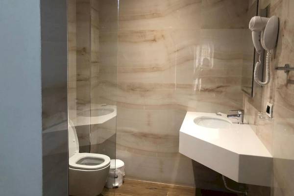 Badezimmer im Vila Mare Hotel mit Glasdusche, Toilette, Waschbecken und Föhn
