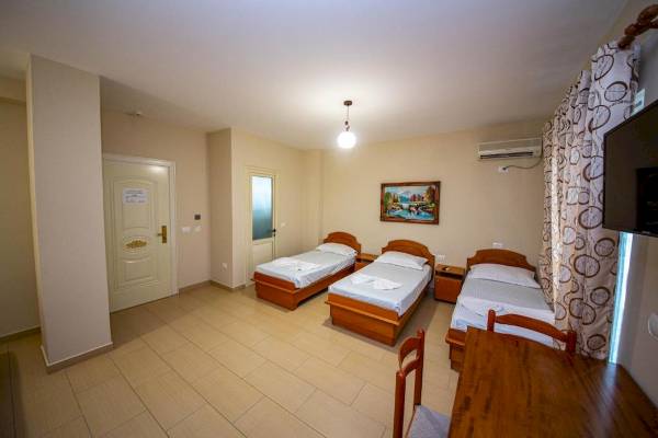 Vila Mare Hotelzimmer mit drei Betten, Nachttischen und einem Tisch.