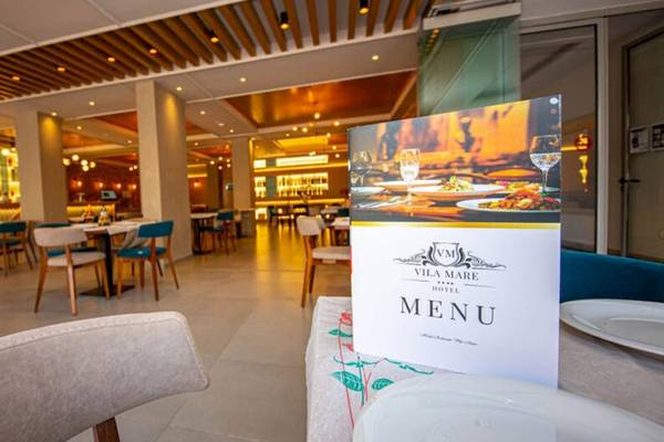 Innenansicht des Restaurants im Vila Mare Hotel mit Tischen, Stühlen und einem Menüschild.