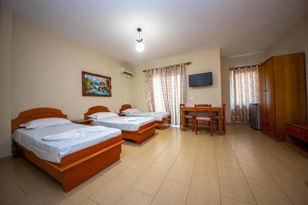 Drei Schlafzimmer im Vila Mare Hotel mit Betten, Tisch und Fernseher.