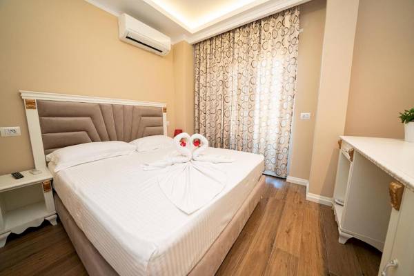 Innenansicht eines Hotelzimmers von Vila Mare mit zwei weißen Bettdecken und einem Bett, auf dem zwei gedrehte weiße Handtücher liegen.