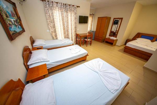 Zimmer im Hotel Vila Mare mit drei Betten, Tisch, Stühlen, Kleiderschrank und Fernseher.