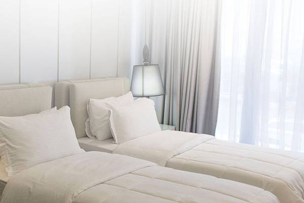 Doppelbett-Zimmer im Demi Hotel mit weißen Möbeln, Bettwäsche und Lampen.