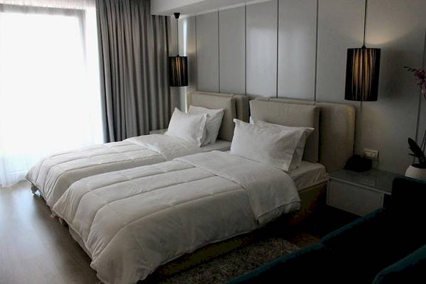Zwei Betten im Schlafzimmer des Demi Hotels, beide mit weißen Decken und Kissen.