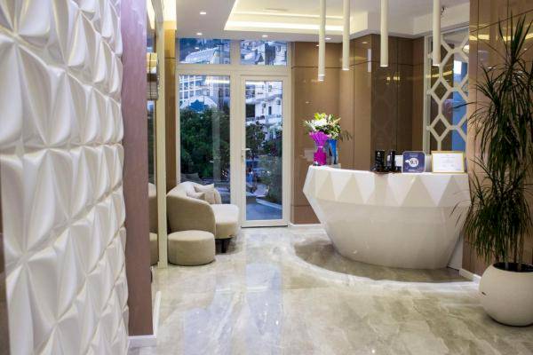 Die Rezeption des Demi Hotels mit moderner weißer Theke und strukturierter Wand.