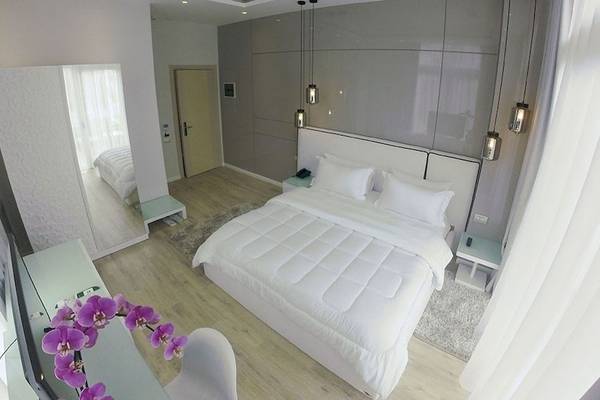 Schlafzimmer im Demi Hotel mit einem großen Bett, weißen Kissen und einem Nachttisch.