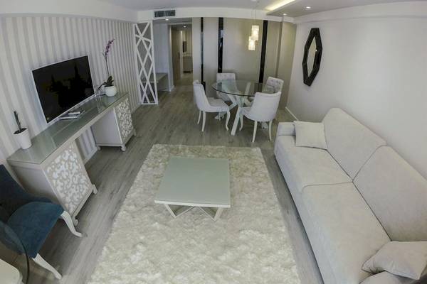 Wohnzimmer im Demi Hotel mit Couch, Tisch, Fernseher und Esstisch.