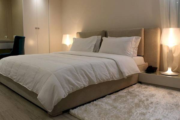 Schlafzimmer im Demi Hotel mit weißem Bett, Kissen, Decken und Lampen auf Nachttischen.