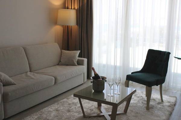 Hotelzimmer mit Sofa, Tisch, Flasche Champagner und zwei Gläsern auf einer Fensterbank.