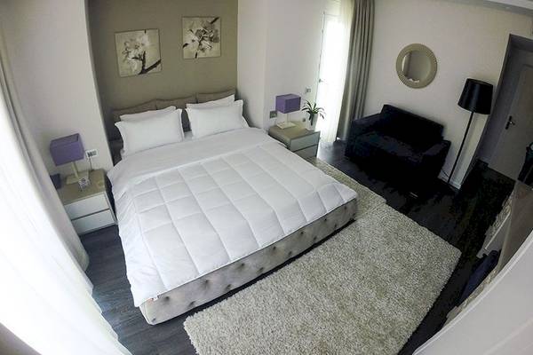 Ein Schlafzimmer im Demi Hotel mit einem großen Bett, weißen Decken, Kissen und einem weißen Teppich.