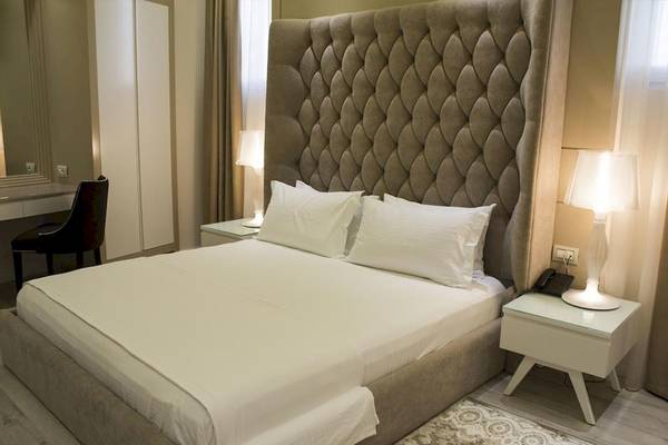 Schlafzimmer im Demi Hotel mit einem Doppelbett, zwei Nachttischen und zwei Lampen.