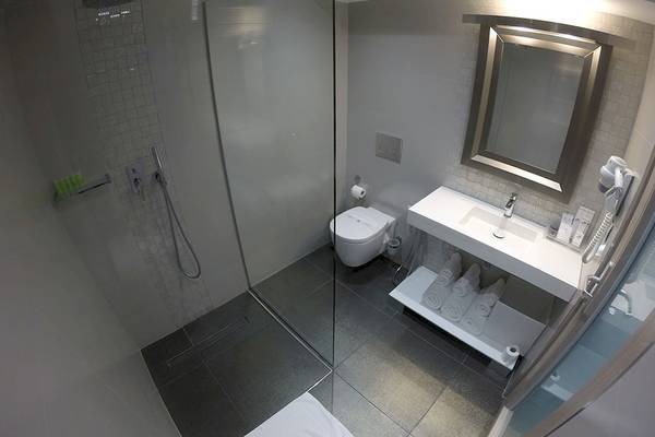 Badezimmer des Demi Hotel mit Dusche, Toilette, Waschbecken und Handtuchtrockner.