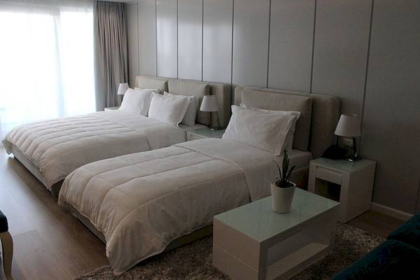 Zwei Betten im Schlafzimmer des Demi Hotels mit weißen Decken und Kissen.