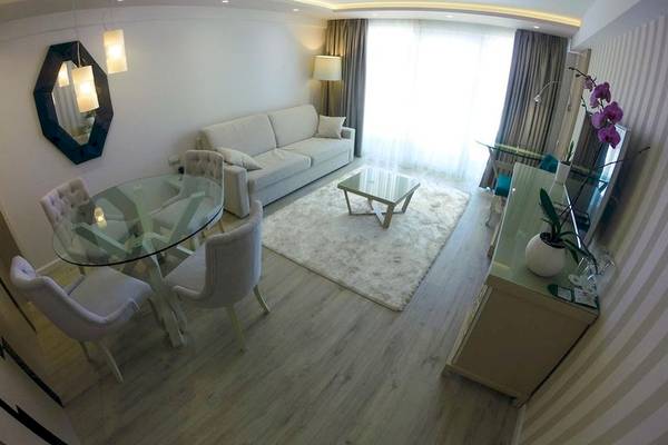 Wohnzimmer im Demi Hotel mit weißem Sofa, Glastisch und modernen Möbeln.