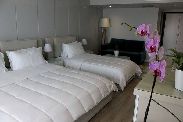 Zwei geräumige Betten mit weißen Decken in einem Schlafzimmer im Demi Hotel.
