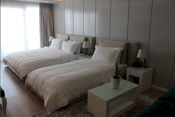 Zwei Betten im Schlafzimmer des Demi Hotels mit weißen Decken und Kissen.