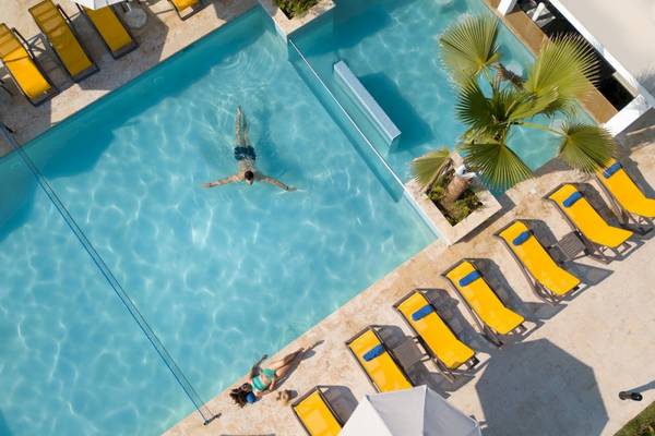 Hotel Emotions By Hodelpa in Puerto Plata mit Poolbereich, Gästen und Sonnenschirmen.