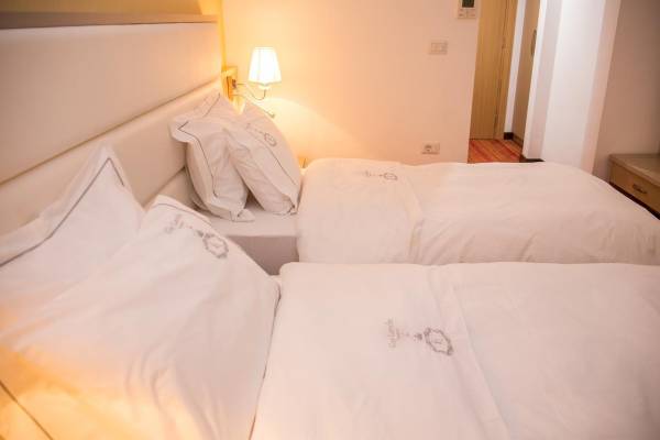 Doppelzimmer im Santa Quaranta Premium Resort mit drei Betten und weißen Laken.