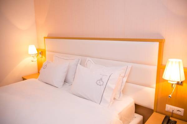 Bett im Zimmer des Santa Quaranta Premium Resorts mit weißen Laken und Kissen.