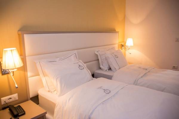 Doppelzimmer im Santa Quaranta Premium Resort mit zwei Betten, weißen Laken und Kissen.