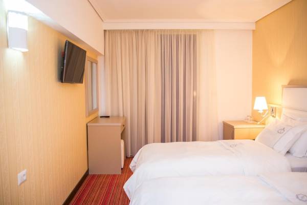 Doppelzimmer im Santa Quaranta Premium Resort mit zwei Betten und einer Fernseher an der Wand.