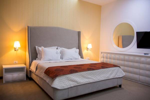 Ein modernes Hotelzimmer mit einem bequemen Bett, einem Spiegel und einem Nachttisch.