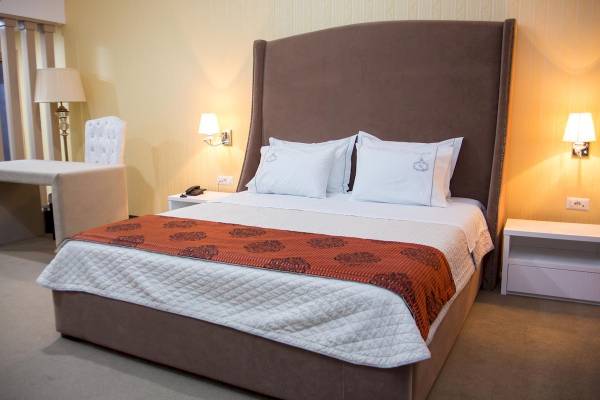 Ein komfortables Hotelzimmer mit einem gepolsterten Bett, weißen Kissen und orangem Bettüberwurf.