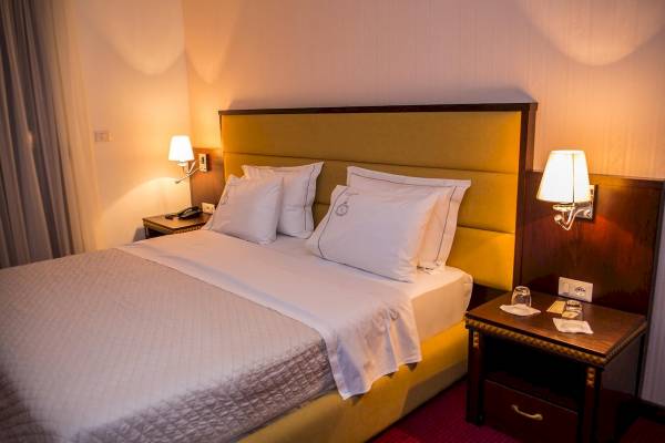 Hotelzimmer im Santa Quaranta Premium Resort mit Bett, Kopfteil und Nachttischen.