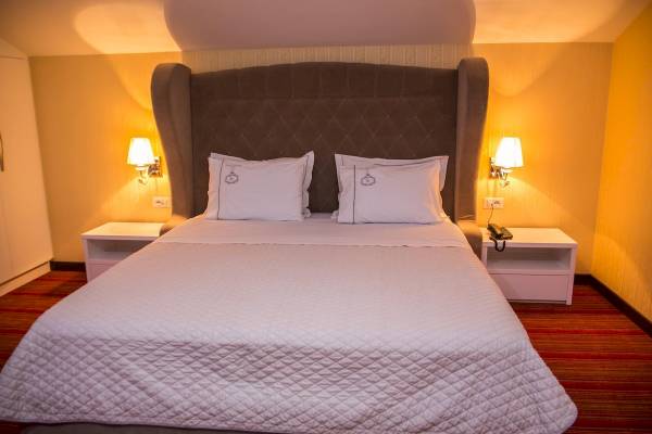 Doppelbettzimmer im Santa Quaranta Premium Resort mit beigem Kopfteil und gelben Wänden.
