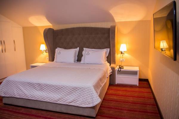 Schlafzimmer im Santa Quaranta Premium Resort mit einem großen Bett und zwei Nachttischen.