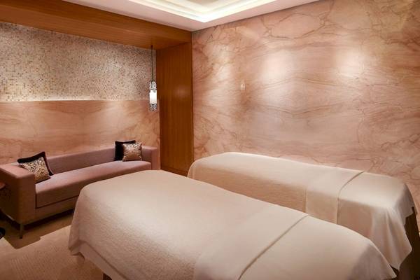 Spa-Behandlungsraum im Grand Hyatt Dubai mit zwei Behandlungsbetten, einem Sofa und marmornen Wänden.