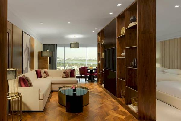 Innenansicht einer Suite im Grand Hyatt Dubai mit Wohnzimmer, Essbereich und Schlafzimmer.