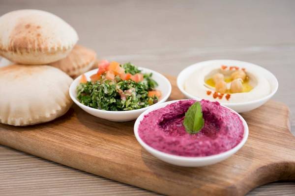 Ein Schneidebrett mit verschiedenen Hummus-Variationen und Pita-Brot