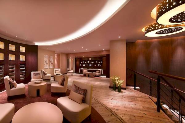 Innenbereich des Grand Hyatt Dubai mit weißen Sesseln, Tischen und Holzboden