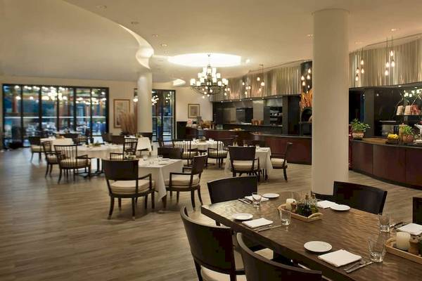Innenansicht des Restaurants im Grand Hyatt Dubai mit Tisch und Stühlen, modernem Design und zentraler Theke.
