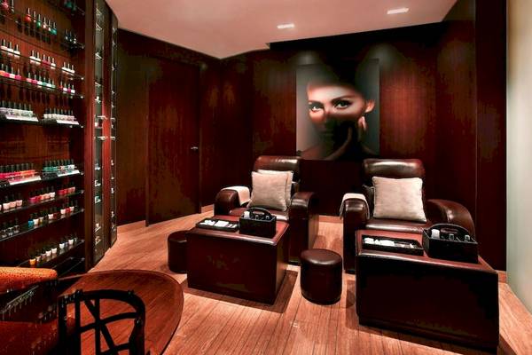 Salonbereich im Grand Hyatt Dubai mit Ledersesseln, Nagellackregalen und einer großen Frau auf der Wand.