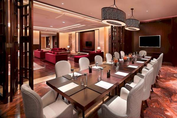 Konferenzraum im Grand Hyatt Dubai mit langem Tisch, weißen Stühlen und rotem Sofabereich.