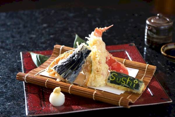 Ein Sushi-Teller mit verschiedenen Sushi-Stücken und einem Schriftzug, der Sushi auf dem Teller sagt.