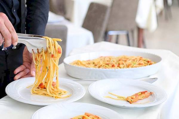Ein Kellner serviert Spaghetti mit Garnelen im Dyrrah Hotel.