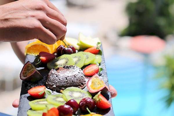 Person, die ein Obstbuffet in der Nähe eines Schwimmbads hält