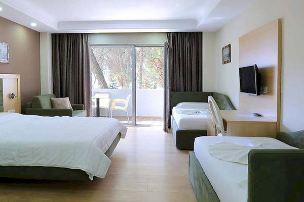Ein Hotelzimmer im Dyrrah Hotel mit zwei Betten, grünen Möbeln und einer Terrasse.