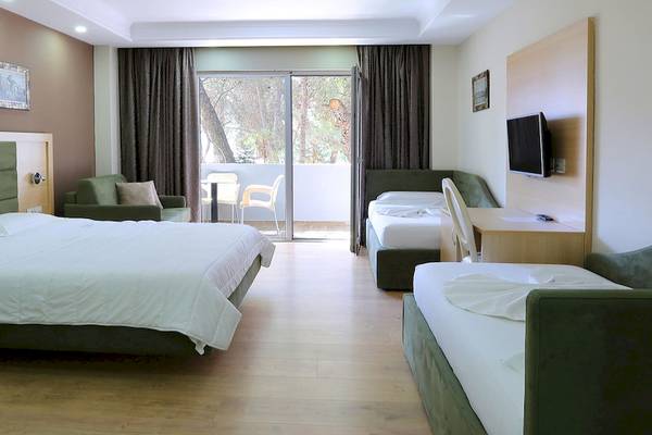 Innenansicht eines Hotelzimmers im Dyrrah Hotel mit einem großen Bett, einem Balkon und einem Fernseher.