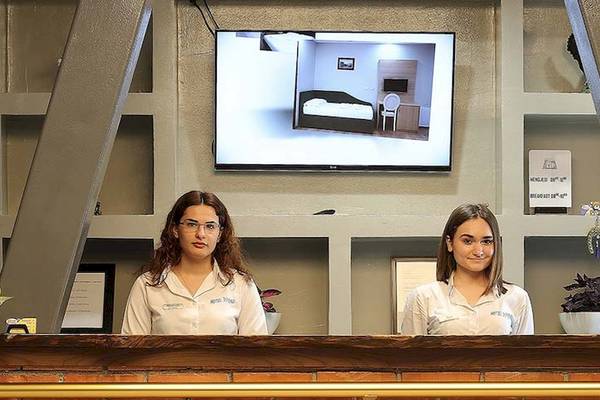 Zwei Frauen an der Rezeption des Dyrrah Hotels, davor eine Anzeige auf einem Monitor.