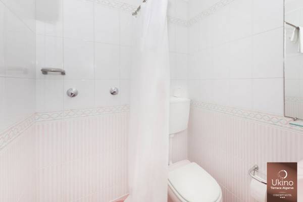 Badezimmer im Ukino Terrace Algarve Hotel mit weißer Dusche und rosa Akzenten.