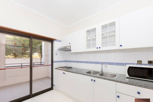 Innenansicht der Küche des Ukino Terrace Algarve Hotels mit weißem Design und Balkonzugang.