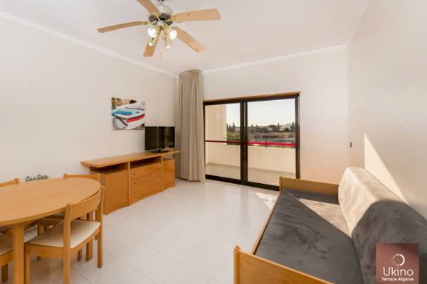 Inneneinrichtung eines Zimmers im Ukino Terrace Algarve Hotel mit Tisch, Stühlen, Fernseher und Balkon