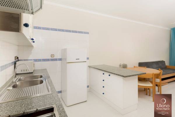 Küche im Ukino Terrace Algarve mit Kühlschrank, Spülbecken und Esstisch.